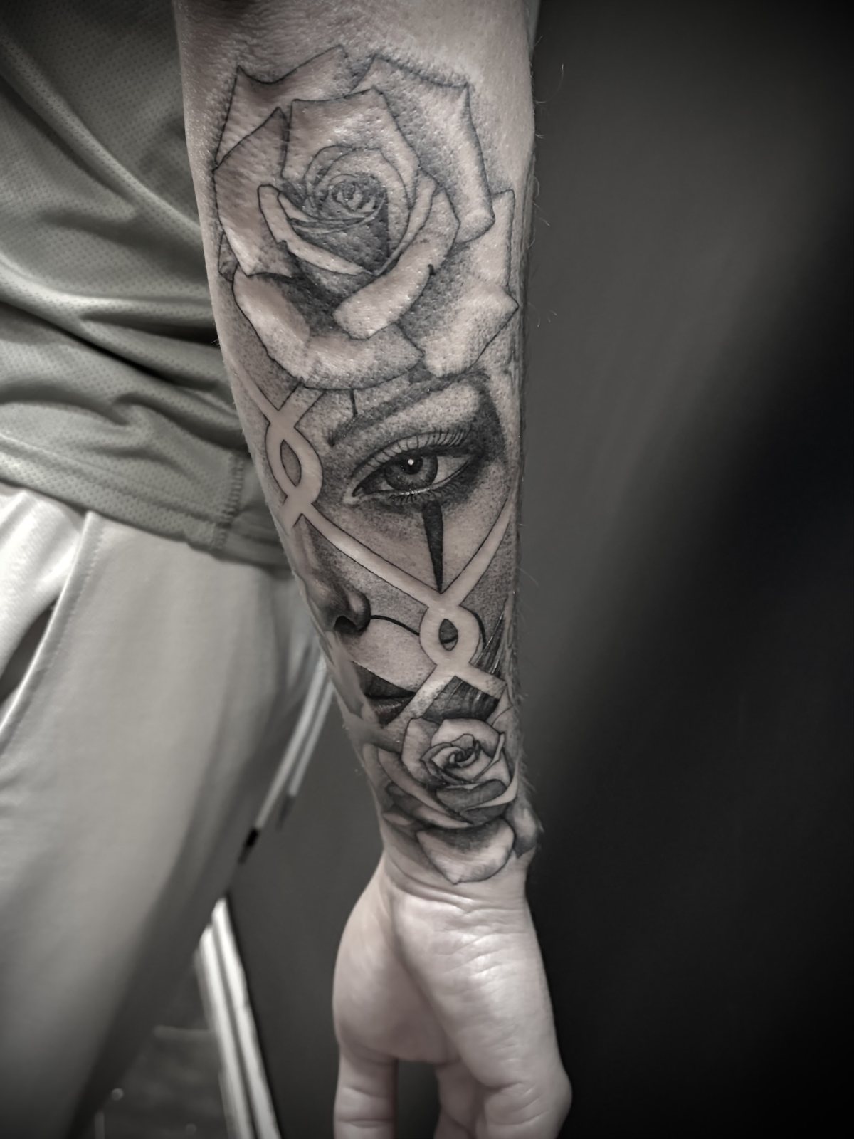 Tattoo van een roos met een oog op de onderarm